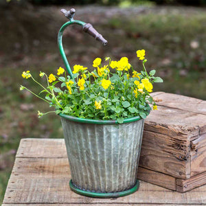 Galvanized metal garden hose tapered planter with yellow flowers